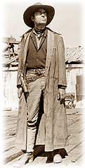 A cowboy wears a duster coat.
